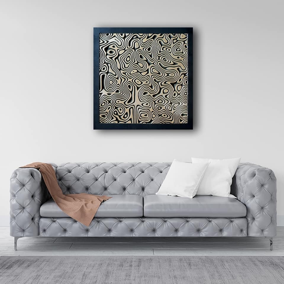 Szary skórzany chesterfield z dwoma białymi poduszkami i beżowym pledem, na ścianie abstrakcyjny obraz w czarnej ramie.