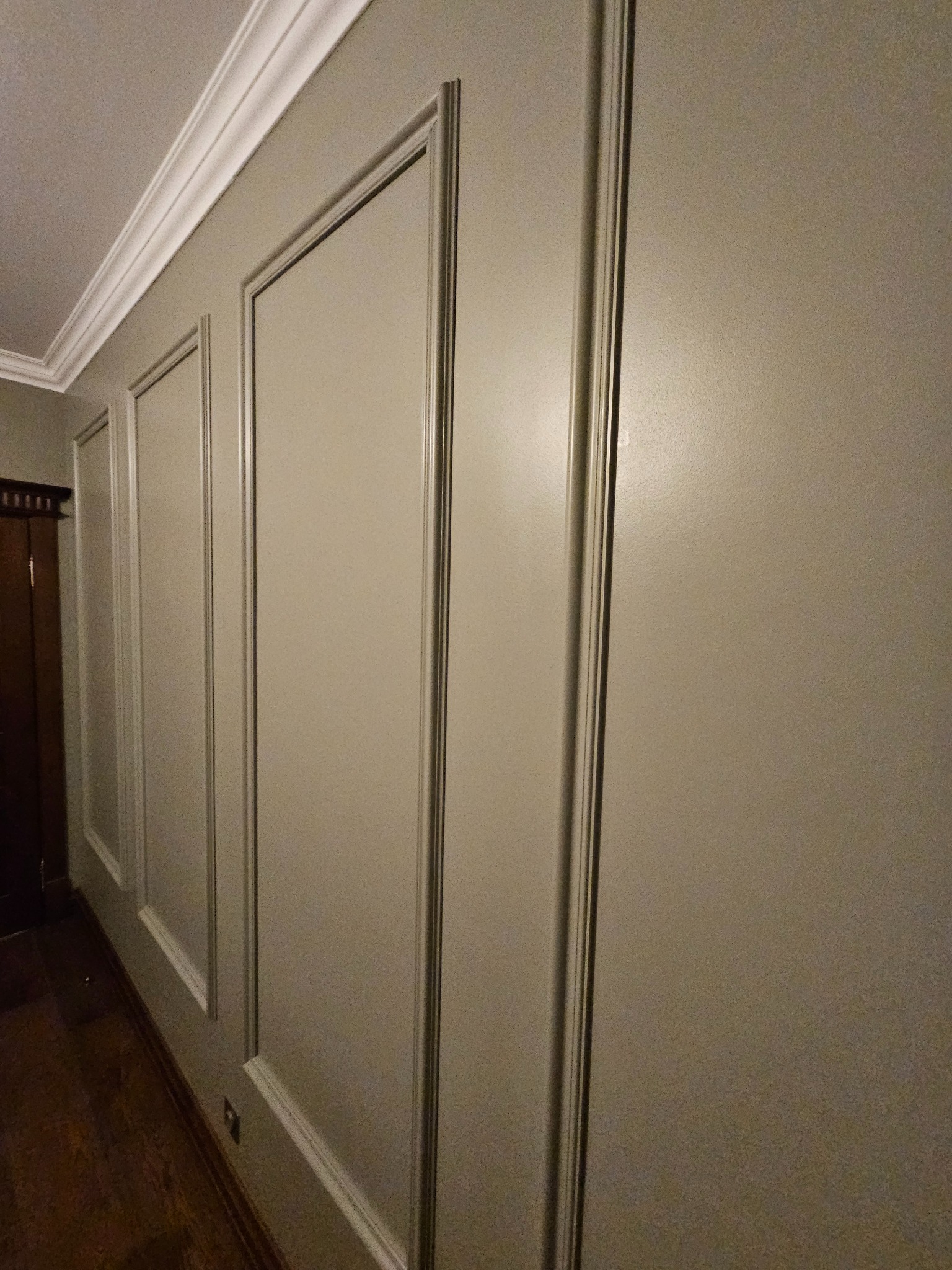 Elegancka ściana z panelami dekoracyjnymi w odcieniach beżu, wykończona listwami przysufitowymi. Widok z boku, ukazujący głębię i detale wykończenia.