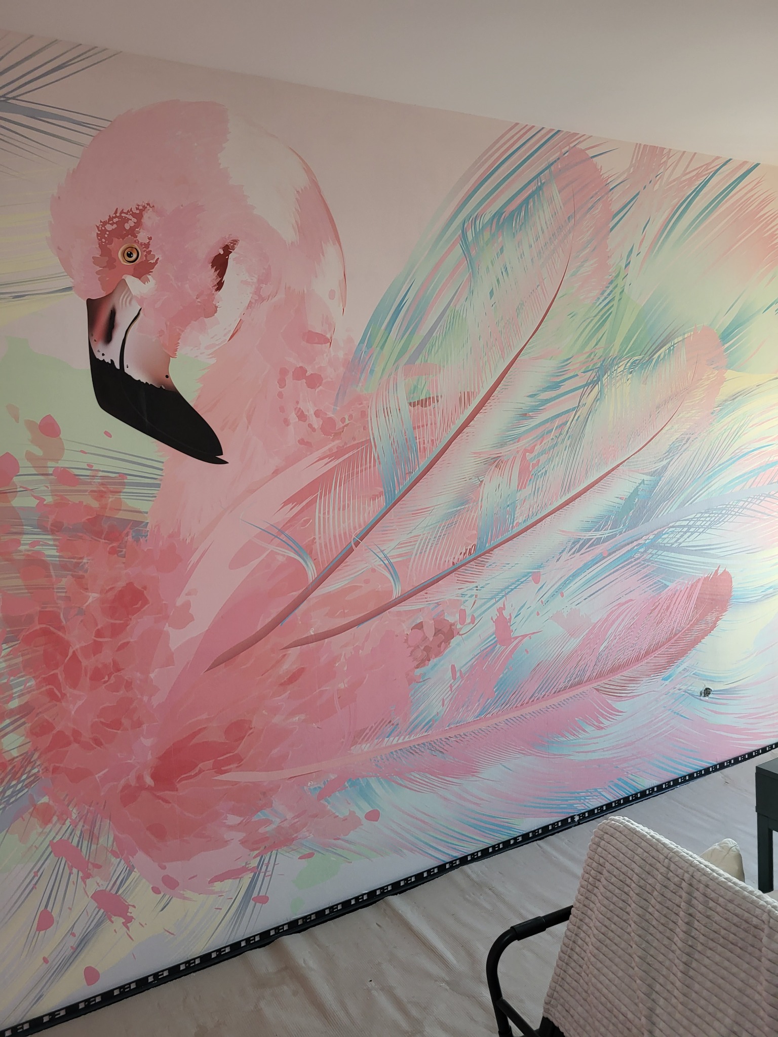 Ręcznie malowana ściana z motywem flaminga w pastelowych odcieniach różu i błękitu, widoczne detale piór i plam farby, oświetlenie LED przy podłodze.
