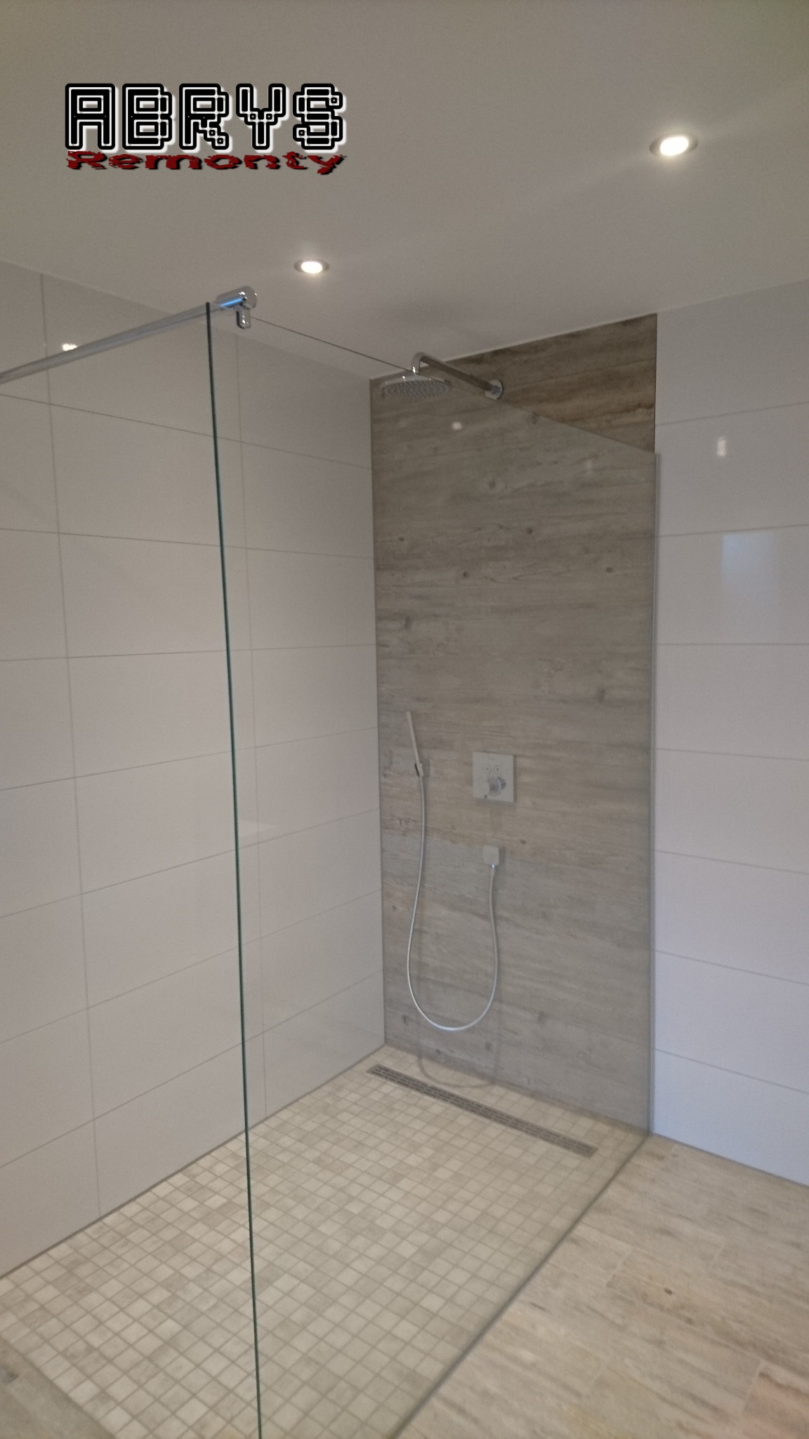 Nowoczesna kabina prysznicowa walk-in z odpływem liniowym, wykończona białymi płytkami i panelem imitującym drewno, oświetlona punktowymi lampami sufitowymi.