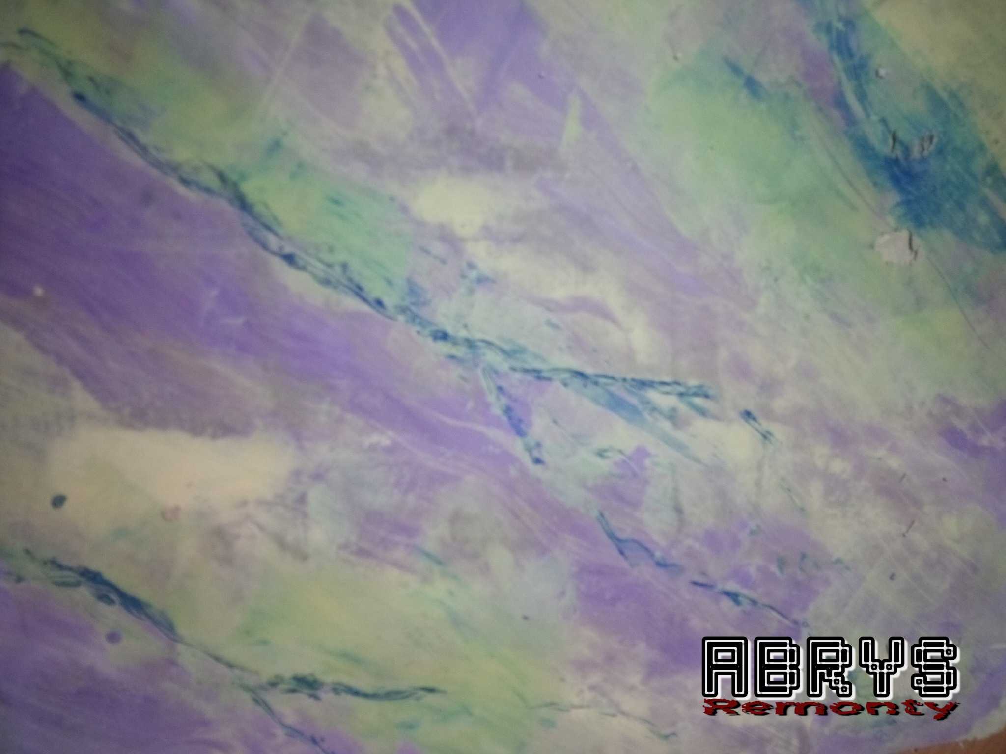 Abstrakcyjna, fioletowo-zielona faktura ściany z logo firmy remontowej w rogu.