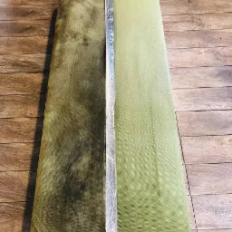 Dzielona na pół poduszka siedziska: po lewej stronie widoczna silna plama i zabrudzenia, po prawej czysta, jasnozielona tkanina po praniu, oddzielona taśmą ochronną.