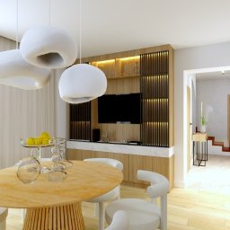 KIMERA Design Studio - Jasna jadalnia z okrągłym stołem i designerską lampą. W tle zabudowa z telewizorem i drewnianymi lamelami. Widok na schody w głębi. Nowoczesny minimalizm.