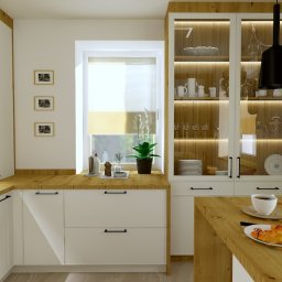 KIMERA Design Studio - Jasna kuchnia z drewnianymi blatami, białymi szafkami i przeszkloną witryną. Na blacie filiżanka kawy i rogalik, a w oknie roślina doniczkowa. Nowoczesny design.