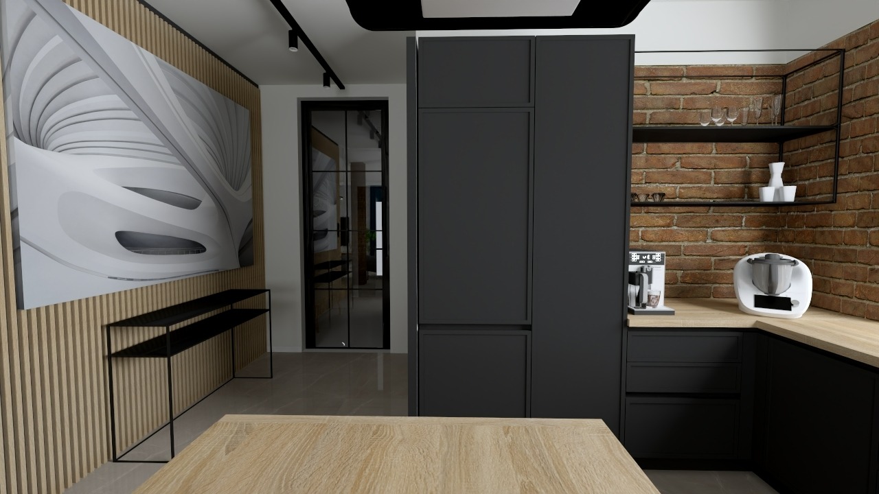 Nowoczesna kuchnia z czarnymi szafkami, drewnianym blatem i ścianą z cegły. Na ścianie grafika w odcieniach szarości. Widoczne akcesoria kuchenne: ekspres do kawy i robot kuchenny.