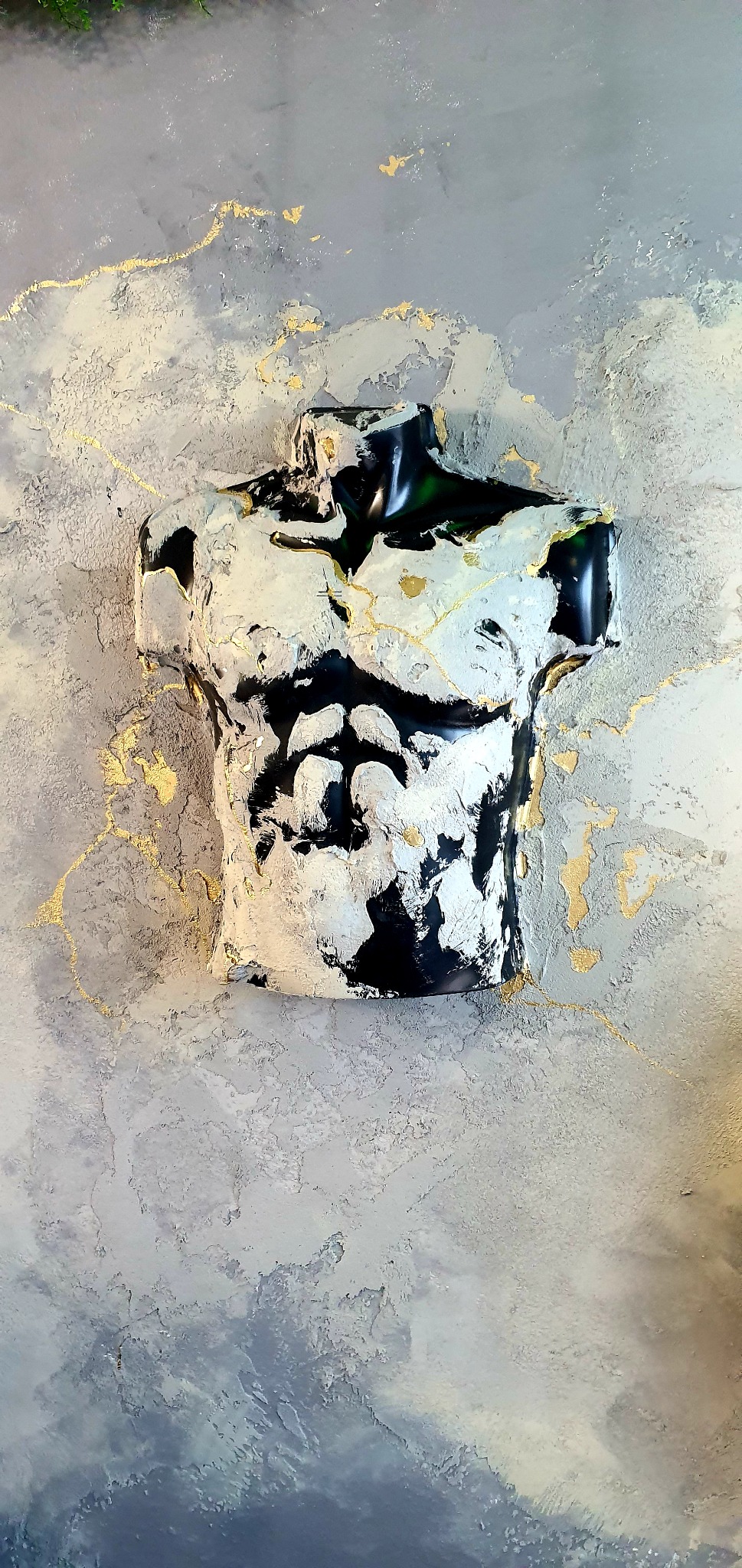 Dekoracyjny tors męski w czarno-białych barwach z elementami złota, umieszczony na szarej ścianie z efektem chmur i złotymi akcentami.