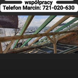 Antiza Usługi CIEŚIELSKO-DEKARSKIE - Wiązar dachowy z elementami konstrukcyjnymi w trakcie montażu, widok z wnętrza budynku na częściowo odsłoniętą konstrukcję dachu i fragmenty muru z cegły.