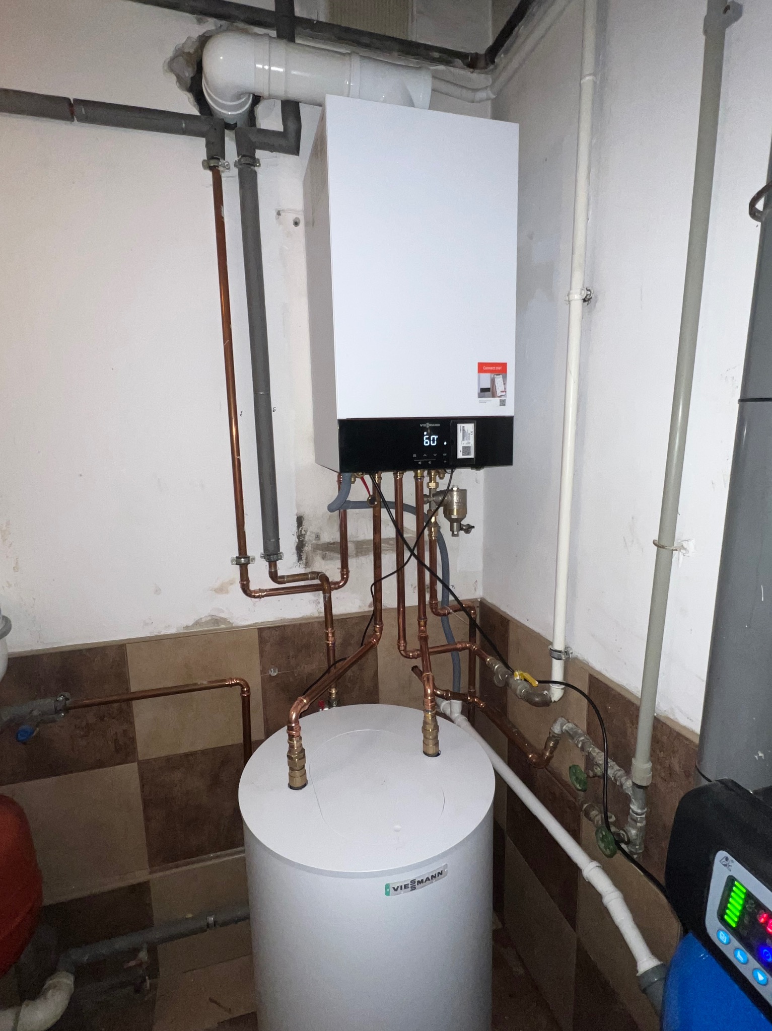 Nowoczesny piec gazowy Viessmann z miedzianą instalacją, zamontowany w pomieszczeniu z częściowo wykończonymi ścianami i widocznym zasobnikiem wody.