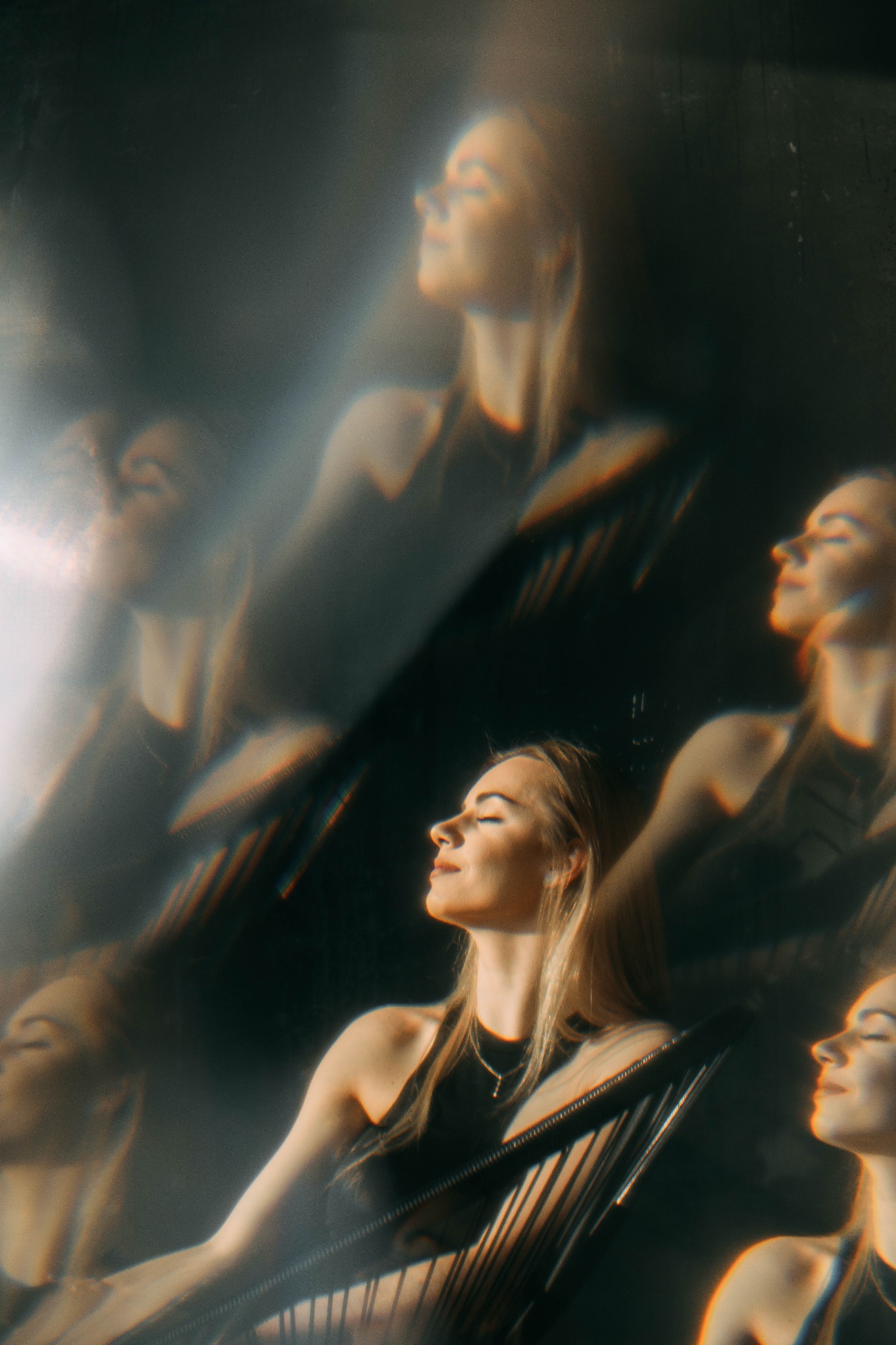 Portret kobiety z blond włosami, z zamkniętymi oczami, uchwycony w artystycznym ujęciu z efektem multiplikacji i rozproszonego światła.