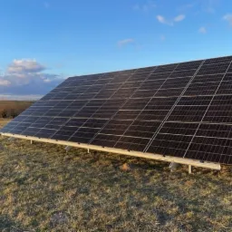 Panel słoneczny na metalowej konstrukcji, zainstalowany na łące w słoneczny dzień.