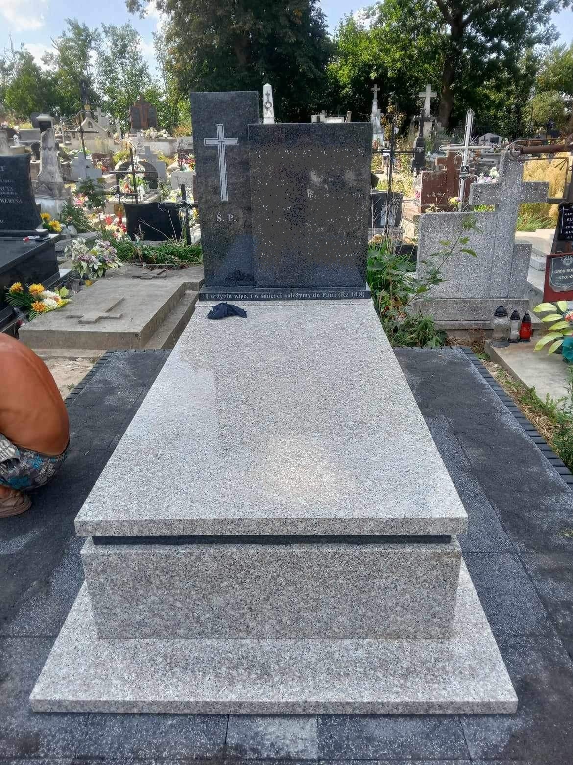 Jasnoszary, granitowy pomnik z ciemnoszarą tablicą i krzyżem, umieszczony na cmentarzu, z widocznym napisem 'I w życiu i w śmierci należymy do Pana (Rz 14,8)'.