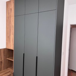 RSIFurniture - Szara szafa na wymiar z drewnianymi elementami w Szczecinie. Minimalistyczny design, czarne uchwyty, zabudowa od podłogi do sufitu, widok z boku.