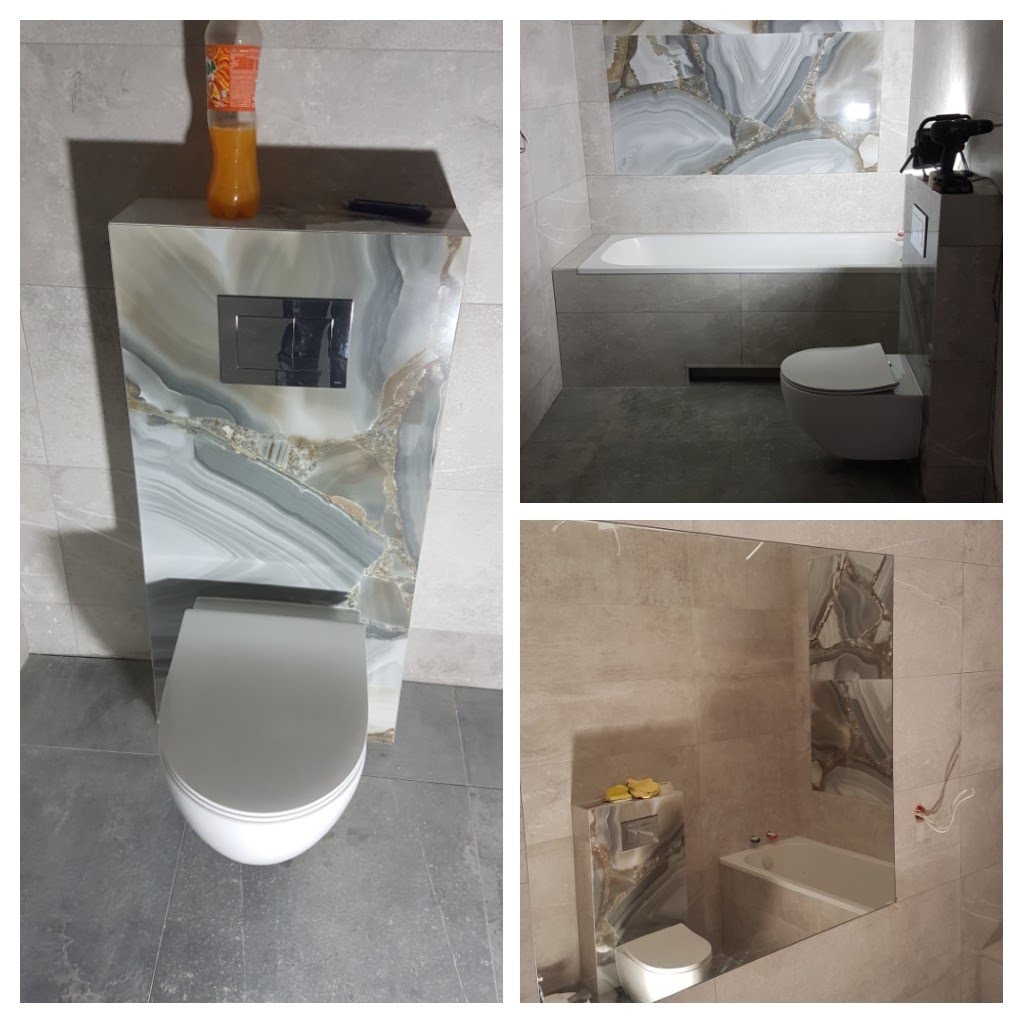 Nowoczesna łazienka po remoncie z podwieszaną toaletą ze spłuczką ukrytą w obudowie z płytek imitujących marmur, dopasowanych do płytek na ścianie nad wanną.