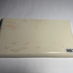 AN-MAR Parapety - Próbka beżowego parapetu z delikatnym wzorem i naklejką 'NB3' w prawym dolnym rogu, leżąca na białym tle.