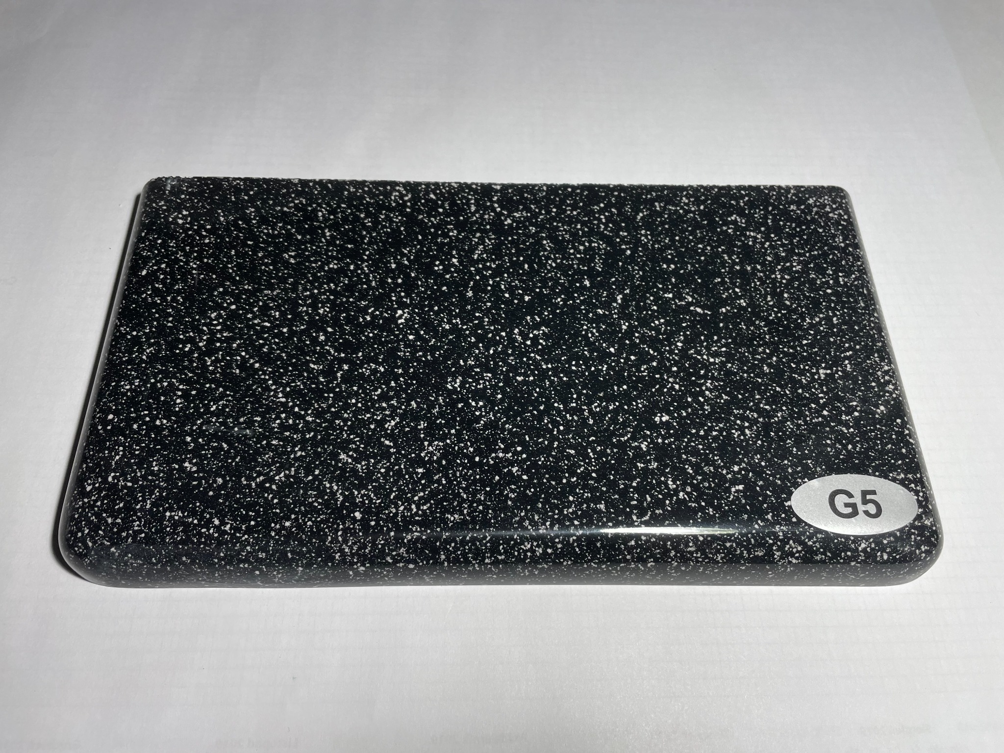 Próbka czarnego blatu z białym wzorem, oznaczona naklejką 'G5', leżąca na białym tle.