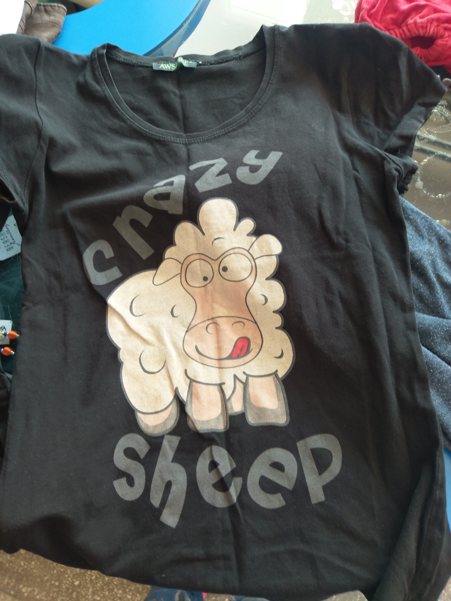 Czarna koszulka z nadrukiem kreskówkowej owcy z wystawionym językiem i napisem 'crazy sheep'.