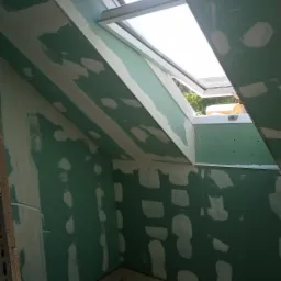 Poddasze we Wrocławiu z oknem dachowym w trakcie montażu płyt kartonowo-gipsowych, widoczne szpachlowane łączenia i fragmenty profili.