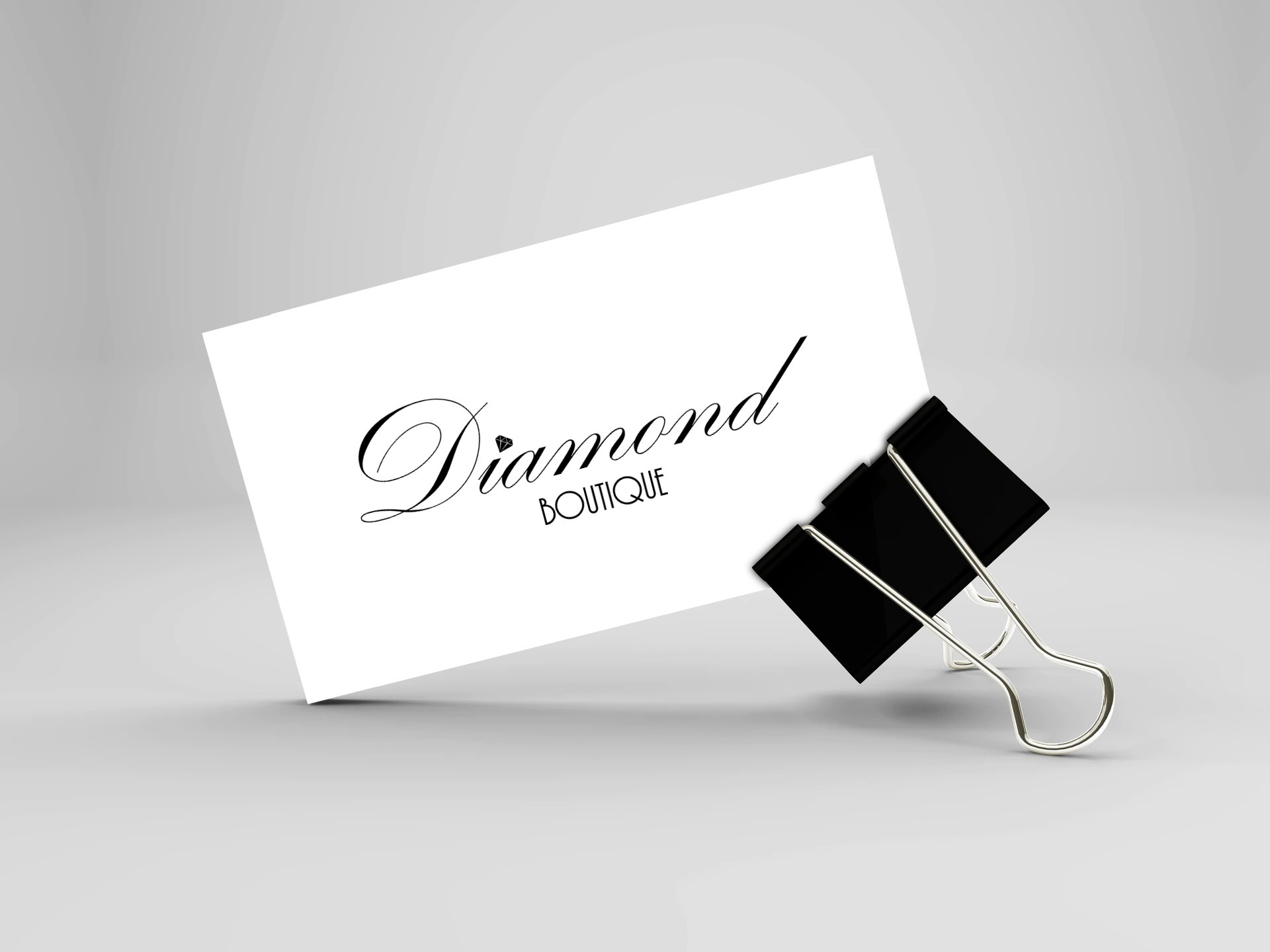 Karta z eleganckim napisem 'Diamond Boutique' przypięta czarnym klipsem na jasnym tle.