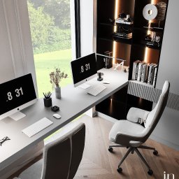 Klein Interiors Julia Klein - Wnętrze biura domowego z dwoma stanowiskami pracy, minimalistyczny design, jasne biurka, ergonomiczne krzesła, duże okno z widokiem na zieleń, regał z podświetleniem i dekoracjami, parkiet w jodełkę.