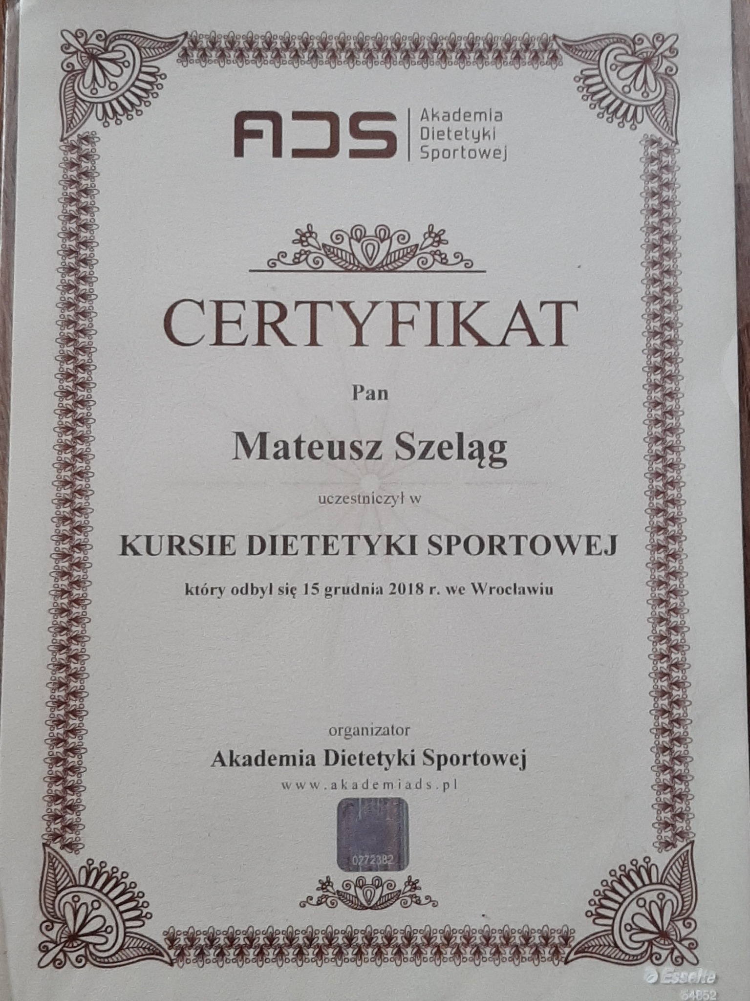 Certyfikat ukończenia kursu dietetyki sportowej dla Mateusza Szeląga, wydany przez Akademię Dietetyki Sportowej z Wrocławia, z datą 15 grudnia 2018 roku, z ozdobną ramką.