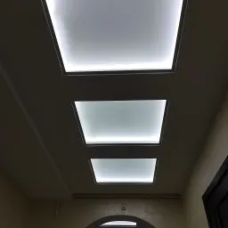 Sufit z trzema kwadratowymi panelami LED w Przemyślu, widok z dołu, ciepłe oświetlenie.