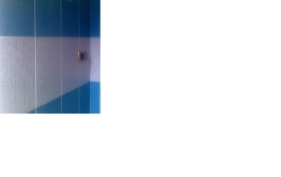 Fragment ściany wyłożonej biało-niebieską glazurą z widocznym gniazdkiem elektrycznym.