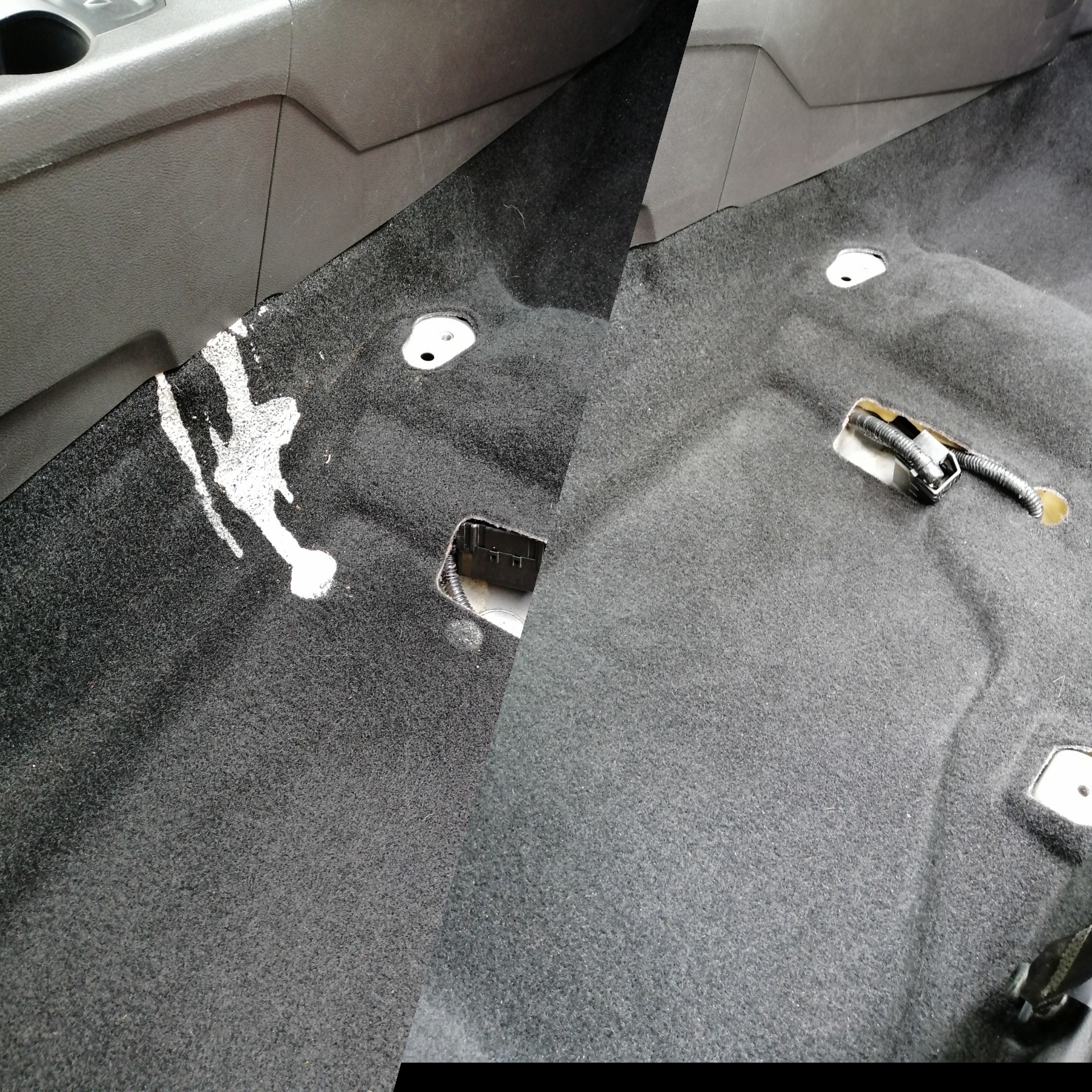 Częściowo zdemontowana, czarna wykładzina podłogowa samochodu z plamą po prawej stronie i widocznymi otworami montażowymi.