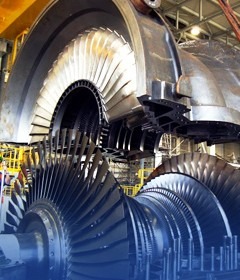 Turbina przemysłowa z widocznymi łopatkami wirnika, metalowa obudowa, duży rozmiar, oświetlenie przemysłowe.