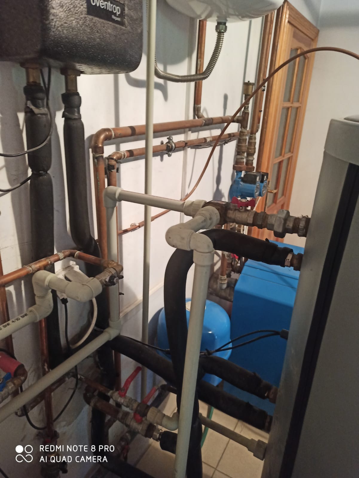 Złożona instalacja grzewcza z rur miedzianych i plastikowych, zbiorników wyrównawczych oraz pomp obiegowych w kotłowni, widoczne elementy systemu Oventrop.