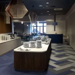 Wnętrze restauracji w Bielawie z niebieską wykładziną w geometryczny wzór i drewnianymi elementami wystroju.