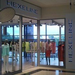 NOVA Technologie Obiektowe Sp.J. - Wejście do sklepu odzieżowego Hexeline z wystawą manekinów w ubraniach w pastelowych kolorach i błyszczącą podłogą z płytek.