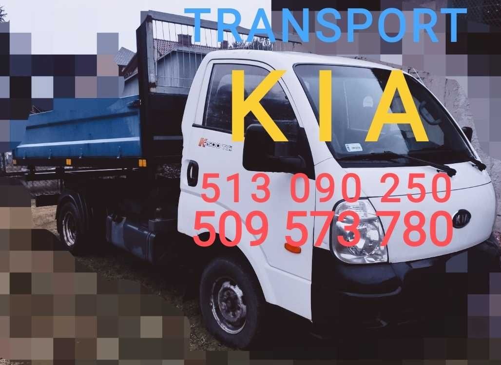 Biały samochód dostawczy marki KIA z otwartą skrzynią ładunkową, z naniesionymi numerami telefonów kontaktowych na karoserii.