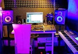 Profesjonalne studio nagrań z monitorem, mikserem, klawiaturą i panelami akustycznymi w fioletowym oświetleniu.