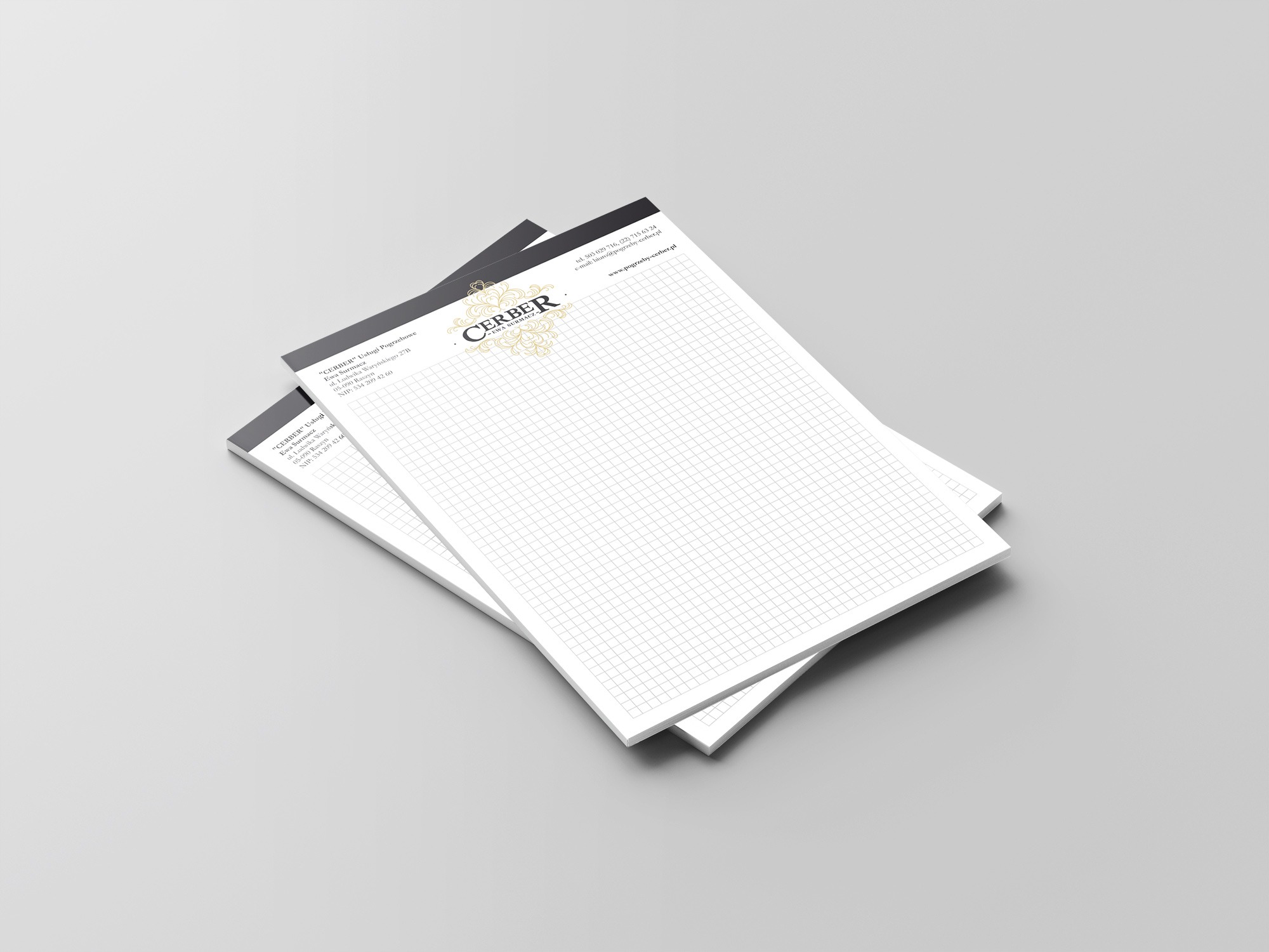 Dwa notesy firmowe z logotypem i danymi kontaktowymi firmy 'CERBER' leżące na szarym tle, widoczne adres, NIP, numer telefonu i adres strony internetowej.