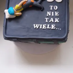 Tort urodzinowy w kształcie walizki z figurką śpiącego nurka i napisem '50 to nie tak wiele...'