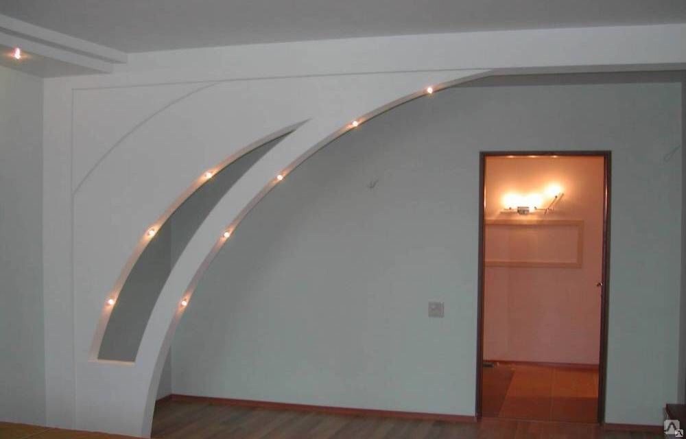 Aranżacja wnętrza z łukową konstrukcją z podświetlanej zabudowy na ścianie, widok na drzwi do innego pomieszczenia z oświetleniem.