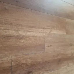 Ułożone panele podłogowe w odcieniach brązu z wyraźną strukturą drewna, widoczne łączenia między panelami, ułożone w klasyczny wzór.