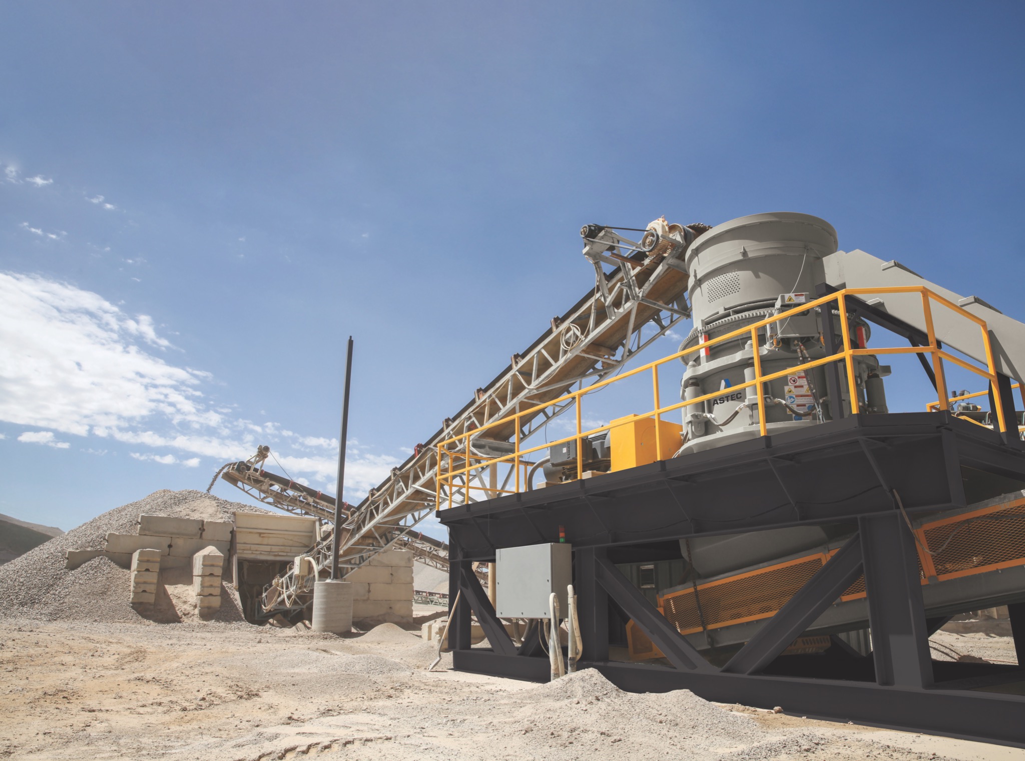 Kopalnia odkrywkowa z taśmociągiem transportującym kruszywo na hałdę, widok z dołu na błękitne niebo z chmurami.