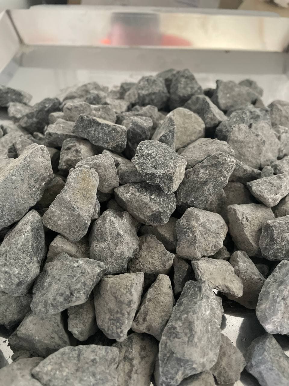 Kupa szarego, łamanego kamienia na metalowej tacy, widok z bliska.