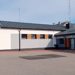 Budynek OSP Hodocice po remoncie elewacji, z nowym dachem z blachy trapezowej, oknami z drewnopodobną okleiną i odświeżonymi kolorami ścian.