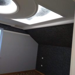 Krzysztof Lis - Pokój po remoncie: ciemna tapeta na skośnej ścianie, jasna ściana, parkiet w jodełkę i designerski sufit podwieszany z oświetleniem.