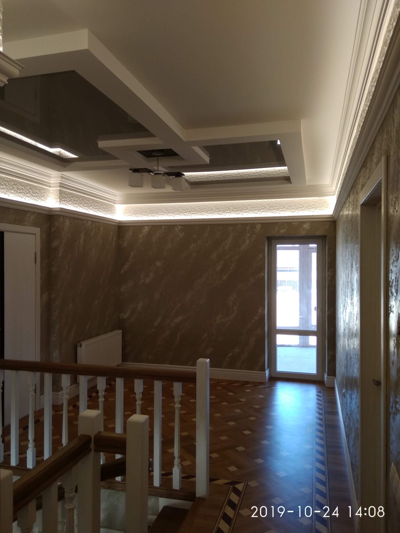 Wykończone wnętrze: dekoracyjny sufit podwieszany z oświetleniem LED, ściany z efektem marmuru, parkiet w jodełkę i drewniana balustrada schodów.