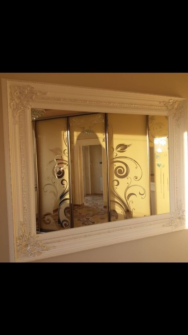 Wbudowana szafa z przesuwnymi drzwiami, zdobiona ornamentami roślinnymi, widoczna w ozdobnej ramie lustra.