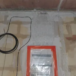 Kable elektryczne ułożone w peszlach, prowadzone po ścianie w surowym stanie, zabezpieczona folią rozdzielnica.