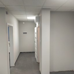 Vitalik Kovalchuk - Jasnoszare wnętrze korytarza z białymi drzwiami, szarą podłogą i klimatyzacją na ścianie, widok po odświeżeniu.