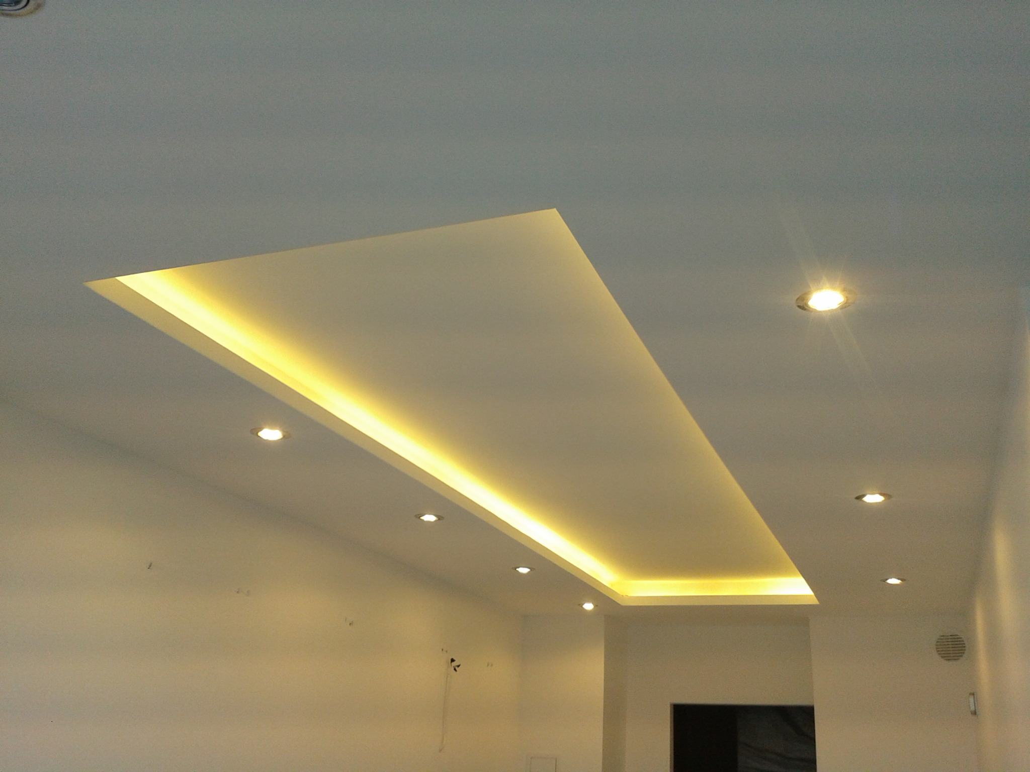 Nowoczesny sufit podwieszany z oświetleniem LED, widoczne punkty świetlne i minimalistyczny design pomieszczenia.