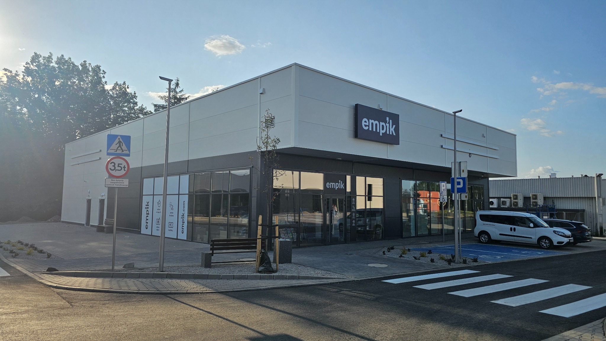 Elewacja budynku Empik z płyt warstwowych w słoneczny dzień. Widoczne logo, okna i otoczenie. Nowoczesna architektura.