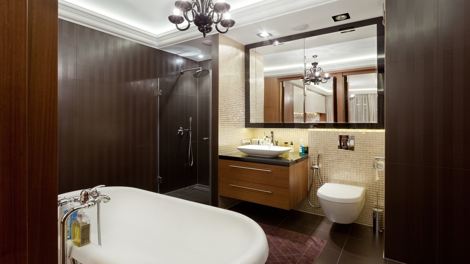 Nowoczesna łazienka z brązowymi płytkami, wolnostojącą wanną, szafką pod umywalkę z drewnianymi frontami i kabiną prysznicową typu walk-in.