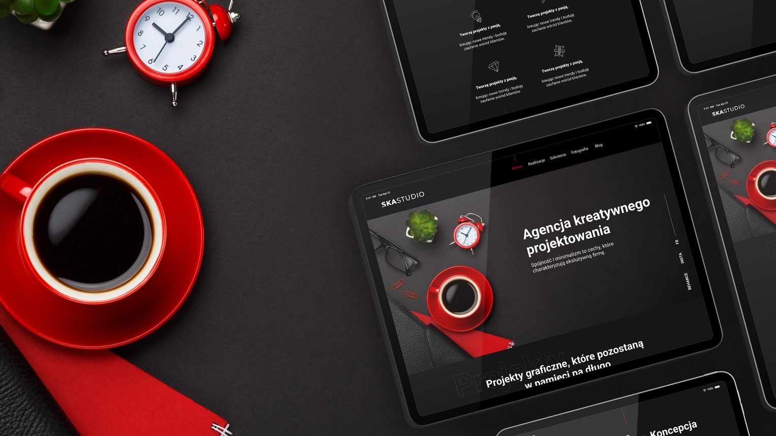 Ekran tabletu prezentujący stronę internetową agencji kreatywnej SKASTUDIO z elementami biurowymi: czerwony zegar, filiżanka kawy, okulary i roślina na ciemnym tle.