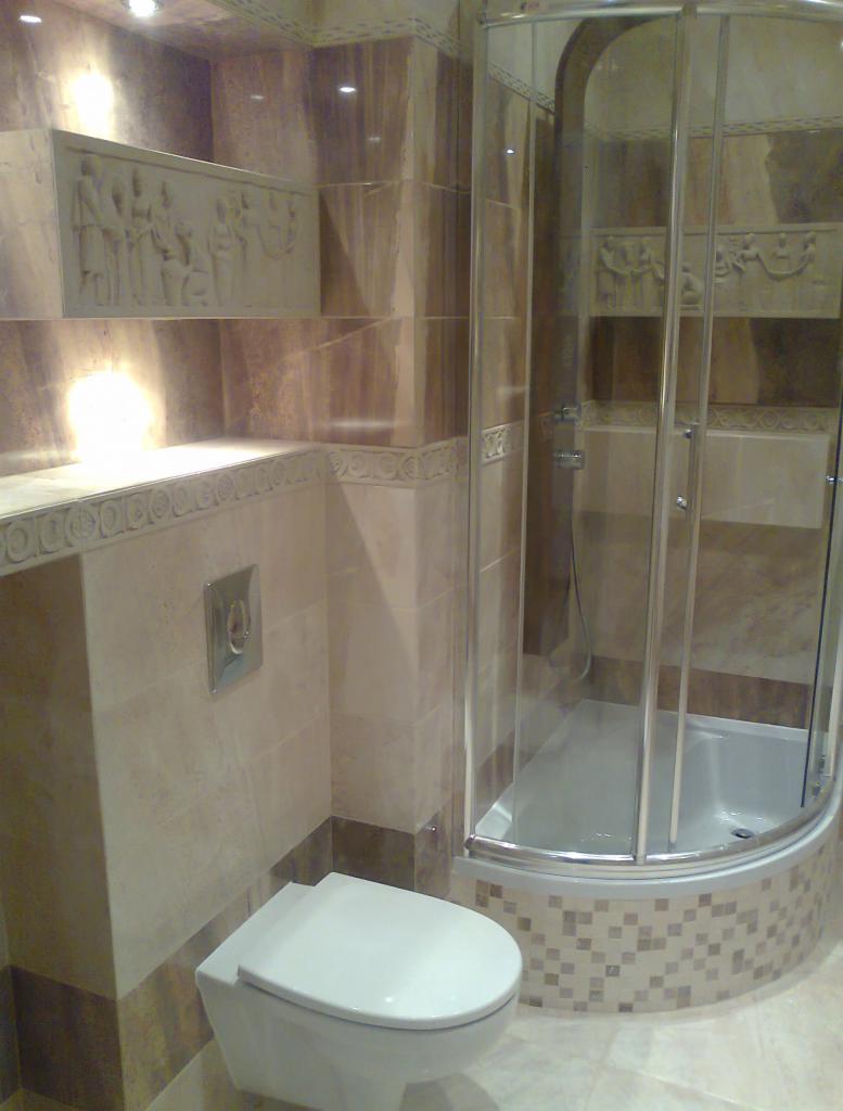 Wykończona łazienka z beżowymi i brązowymi płytkami gresowymi, kabiną prysznicową z zaokrąglonymi drzwiami i podwieszaną toaletą.